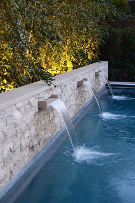 An Outdoor Swimming Pool With Water Spouting From The Side