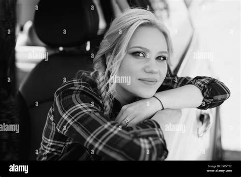 Blonde With Pigtails In A Shirt Jeans Red Shoes And Black Glasses Near A White Car Stock Photo