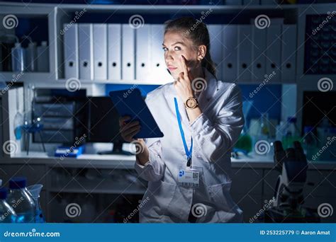 Beautiful Blonde Woman Working At Scientist Laboratory Late At Night Pointing To The Eye