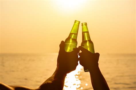 Premium Photo Couple Hands Holding Beer Bottles Clanging At The