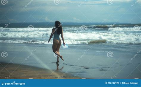 Europejska Dziewczyna W Bikini Chodzi Po Czarnym Piasku Nad Morzem Z