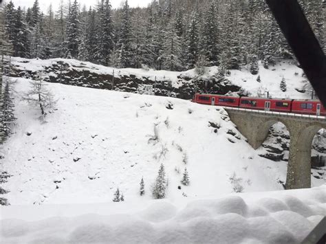 A Red Train Traveling Over A Snow Covered Bridge