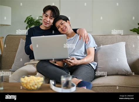 Un jeune homme gay asiatique heureux se détend et embrasse son petit ami tout en regardant un
