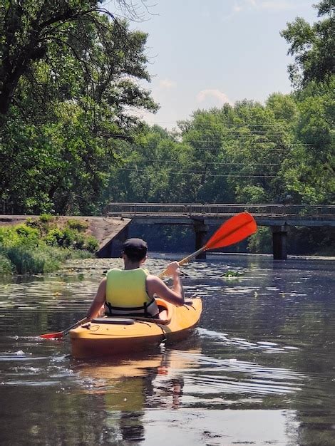 Premium Photo | Kayaking a young man is canoeing down the river rear ...