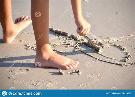 Un Niño Dibuja Un Palo En La Arena Los Dibujos De Los Niños En La Playa