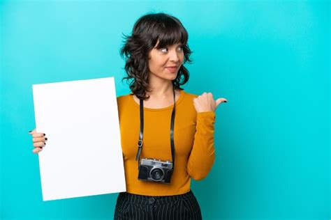 Joven Fot Grafa Mujer Latina Aislada De Fondo Azul Sosteniendo Un Cartel Vac O Y Apuntando Hacia