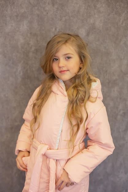 Premium Photo Beautiful Longhaired Blonde Girl In A Pink Warm Jacket On A Gray Background
