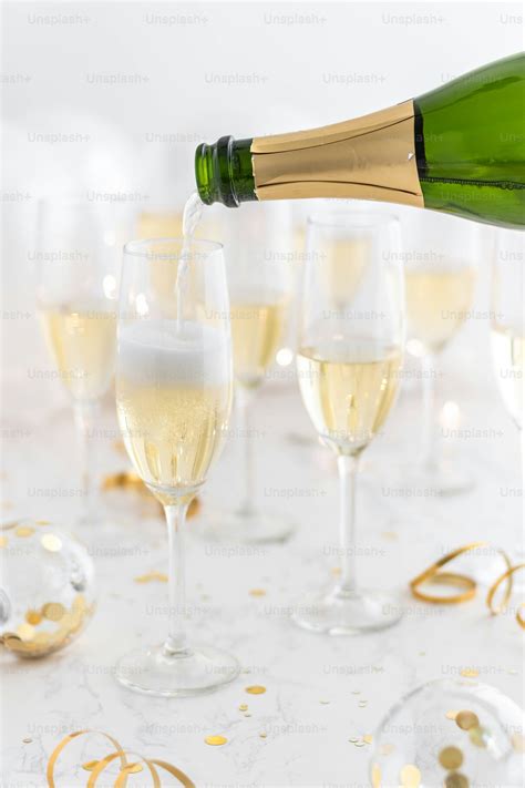 A Bottle Of Champagne Being Poured Into A Glass Photo Glasses Image On Unsplash