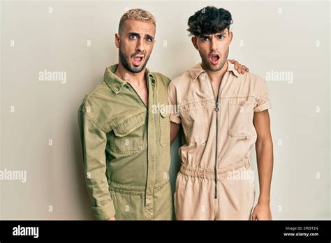 Homosexual Gay Couple Standing Together Wearing Casual Jumpsuit In Shock Face Looking Skeptical