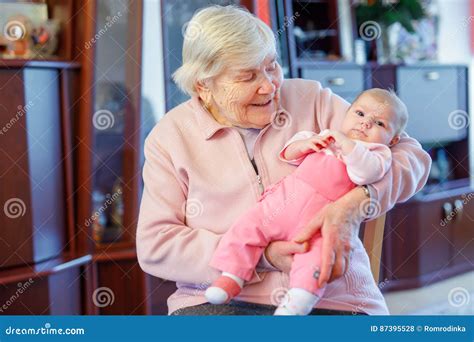 Great Grandmother Holding Newborn Baby Grandchild On Arm Stock Photo