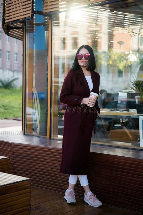 Cheerful Gorgeous Brunette In Winter Fashion Holding Disposable Cup On Urban Background Stock