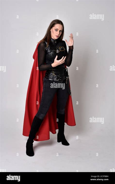 Portrait Of Brunette Girl Wearing Black Leather Catsuit Red Cloak Full Length Standing Pose