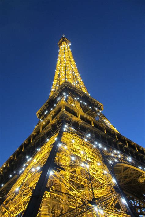 The Eiffel Tower Lit Up At Night With Lights On It S Sides