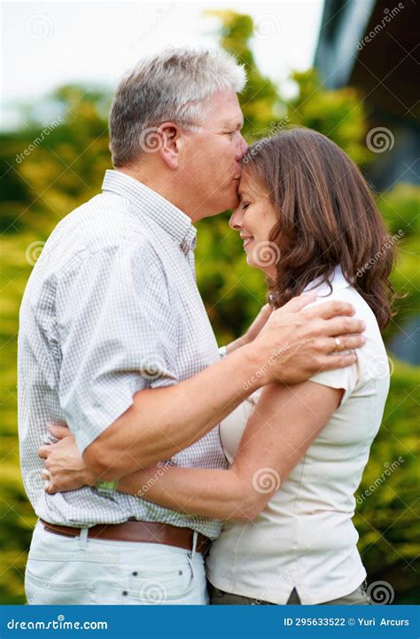 Senior Man Kissing And Woman On Forehead In Backyard Care Or Couple