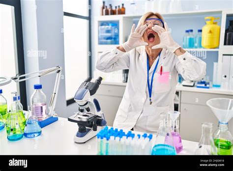 Femme blonde d âge moyen travaillant au laboratoire scientifique criant en colère forte avec les