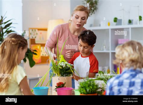 Watching Pupils Experienced Blonde Haired Teacher Watching Her Pupils Watering Flowers At The
