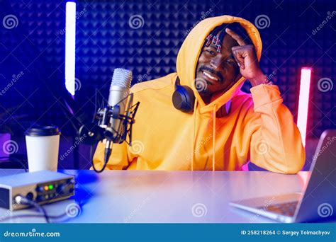 African Radio Host Sitting At Desk Recording In Studio With Microphone