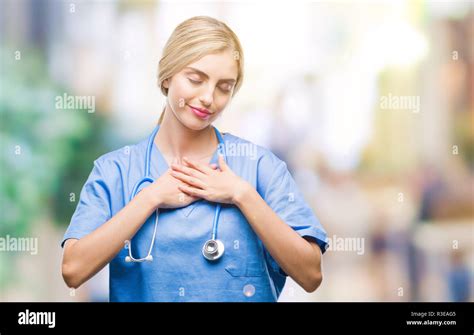 Belle jeune femme blonde infirmière médecin chirurgien isolé au sourire de fond avec les mains