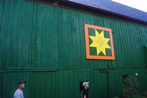 Two People Standing In Front Of A Green Building With A Yellow Star On