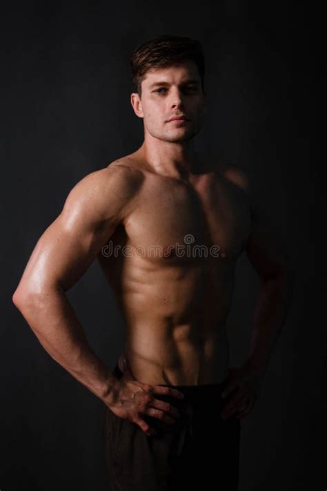 Muscular Bodybuilder Posing With A Naked Torso Against A Black Background Stock Photo Image