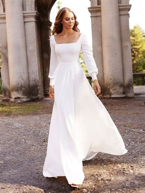 A Woman In A Long White Dress Is Walking Through An Archway With Her