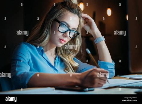 Tired Blonde Caucasian Student In Eyeglasses Writing Something With
