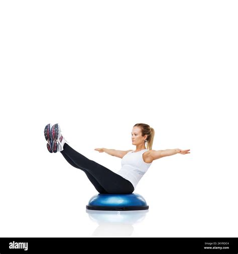 Balancing on a bosu-ball to increase her core strength. An attractive ...