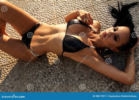 Muchacha Hermosa Con El Pelo Oscuro En El Bikini Que Presenta En La Playa De La Puesta Del Sol