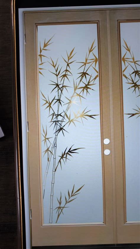 An Open Door With Bamboo Leaves Etched On The Frosted Glass And Wood