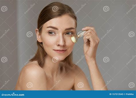 Woman Using Jade Facial Roller For Face Massage At Home Stock Image