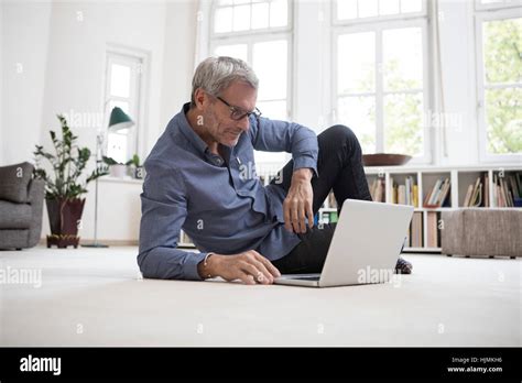 Mature Man At Home Lying On Floor Using Laptop Stock Photo Alamy