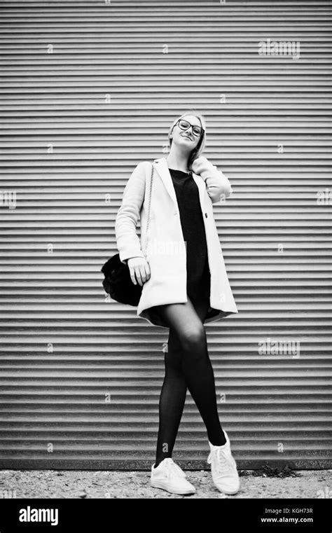 Jeune fille blonde à lunettes et manteau rose contre les volets Photo