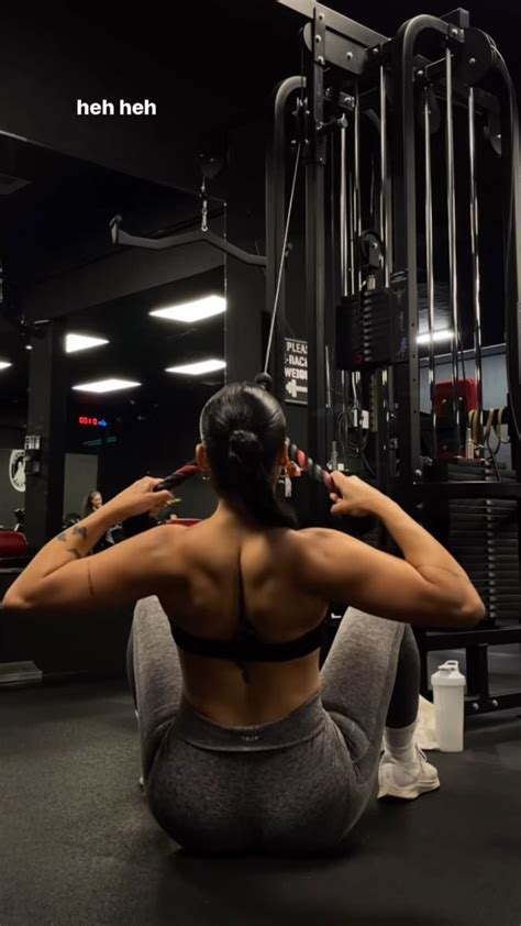 A Woman Squats On The Ground In Front Of A Gym Machine And Holds Her