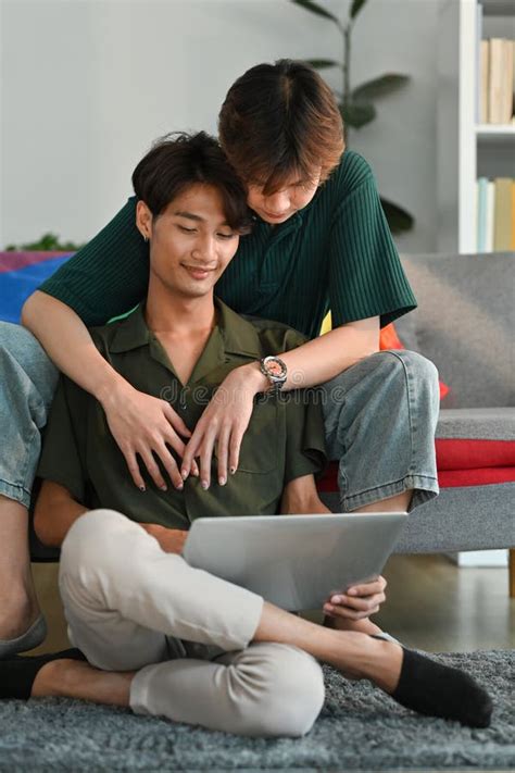 Romantic Happy Gay Couple Embracing And Using Laptop In Living Room LGBT Love And Lifestyle