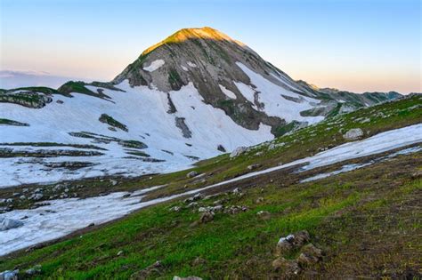 Premium Photo The Snowdrifts And Green Grass On Top Of Mountains In