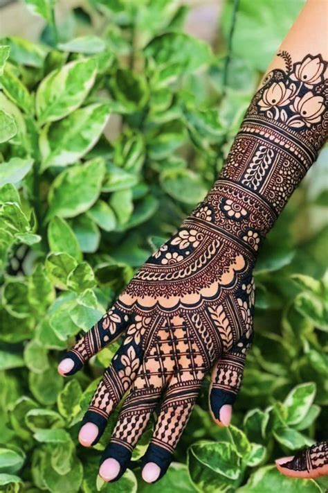 A Woman S Hand With Henna Tattoos On It And Green Leaves In The Background