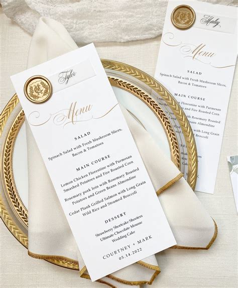 A Table Setting With White And Gold Place Cards Napkins And Silverware