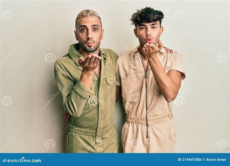 Homosexual Gay Pareja De Pie Juntos Usando Casual Jumpsuit Mirando a La Cámara Soplando Un Beso