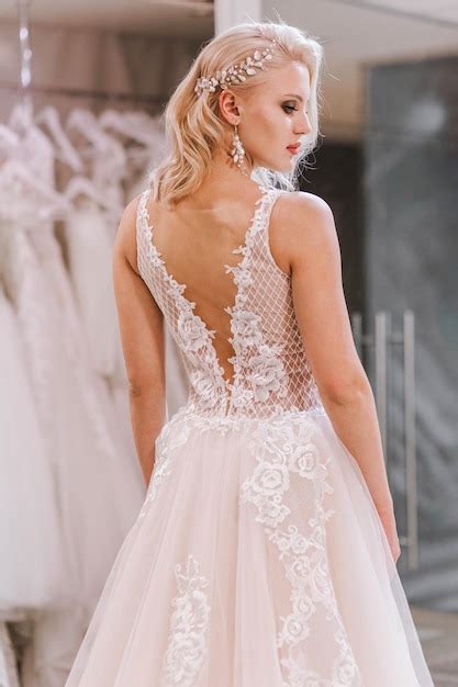 Premium Photo Luxurious Blonde Bride In A Dress With An Open Back Posing In A Bridal Salon