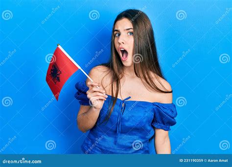 Joven Adolescente De Brunette Sosteniendo La Bandera De Albania Asustado Y Asombrado Con La Boca