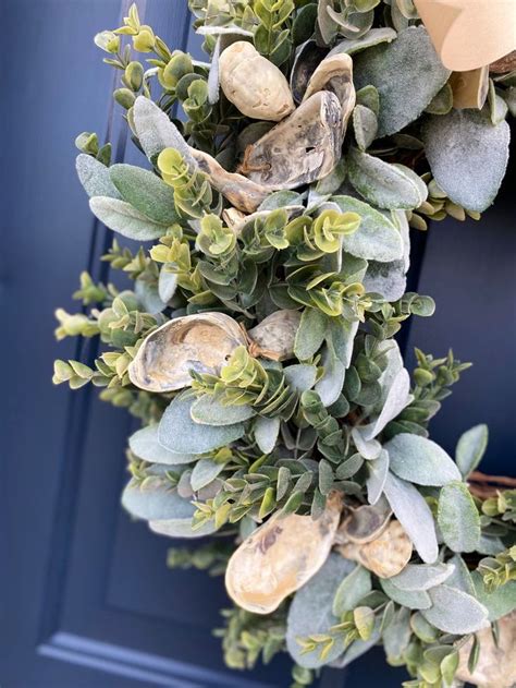 A Wreath Is Hanging On The Front Door With Green Leaves And Other