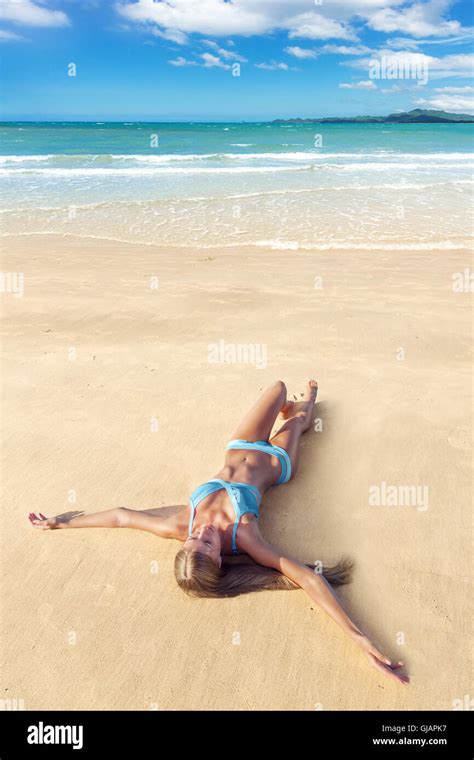 Junge schöne Frau im blauen Bikini auf Sand am tropischen Strand liegend Stockfotografie Alamy