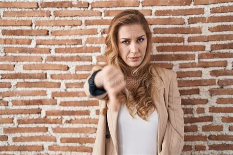 Beautiful Blonde Woman Standing Over Bricks Wall Looking Unhappy And Angry Showing Rejection And