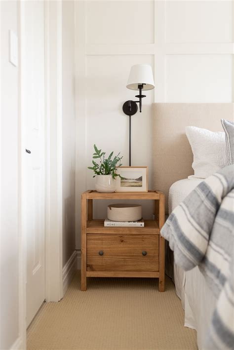 A Bedroom With A Bed Nightstand And Plant On The Night Stand Next To It