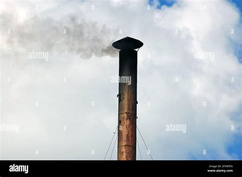 A metal chimney covered in soot with smoke pooring out sideways Stock ...