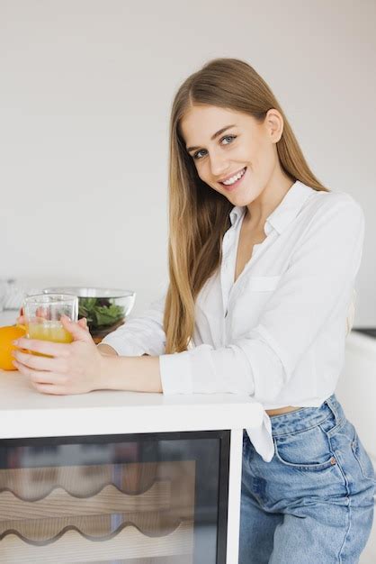 Premium Photo A Happy Cute Blonde Woman Drinks Orange Juice In The Kitchen