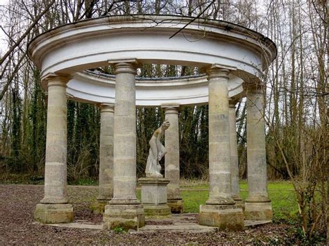 An Outdoor Gazebo With Columns And A Statue In The Center Surrounded