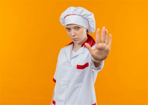Jeune Femme Blonde Confiante Chef Dans Les Gestes Uniformes Du Chef Stop Signe De La Main Isol