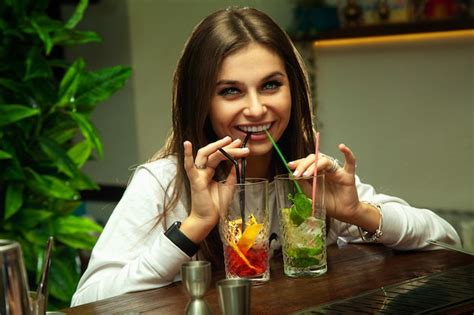 Premium Photo Cute Funny Brunette Girl Drinks Two Cocktails At The Same Time And Smiling On Front
