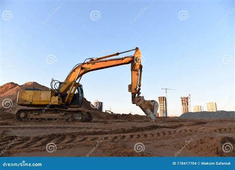 Excavator During Earthmoving At Construction Site On Sunset Background